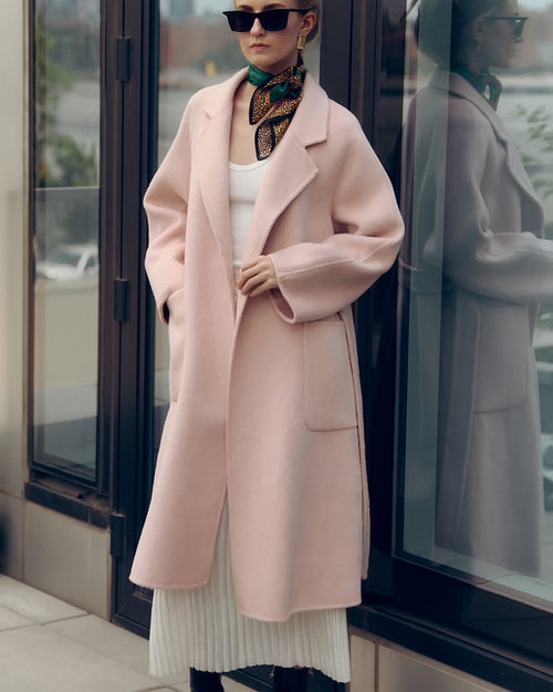 Soft pink oversized wool-blend coat for women featuring wide lapels, drop shoulders, and large patch pockets. Designed with minimalist Japanese tailoring for a relaxed yet elegant silhouette. Perfect for fall and winter layering, this robe-style coat embodies timeless slow fashion and effortless sophistication — crafted for comfort, warmth, and modern everyday wear.